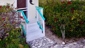 A house with a turquoise roof, a staircase with turquoise railings, and a sign that reads "SUNSET". - Sunset Cottage at The Dragon Cay Resort  (Conch Bar)