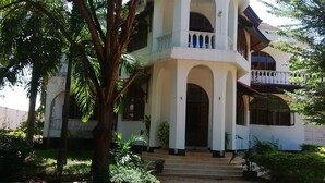 A two-story building with a symmetrical facade, multiple balconies, and a central entrance with steps. - Emerald House (Dar es Salaam)
