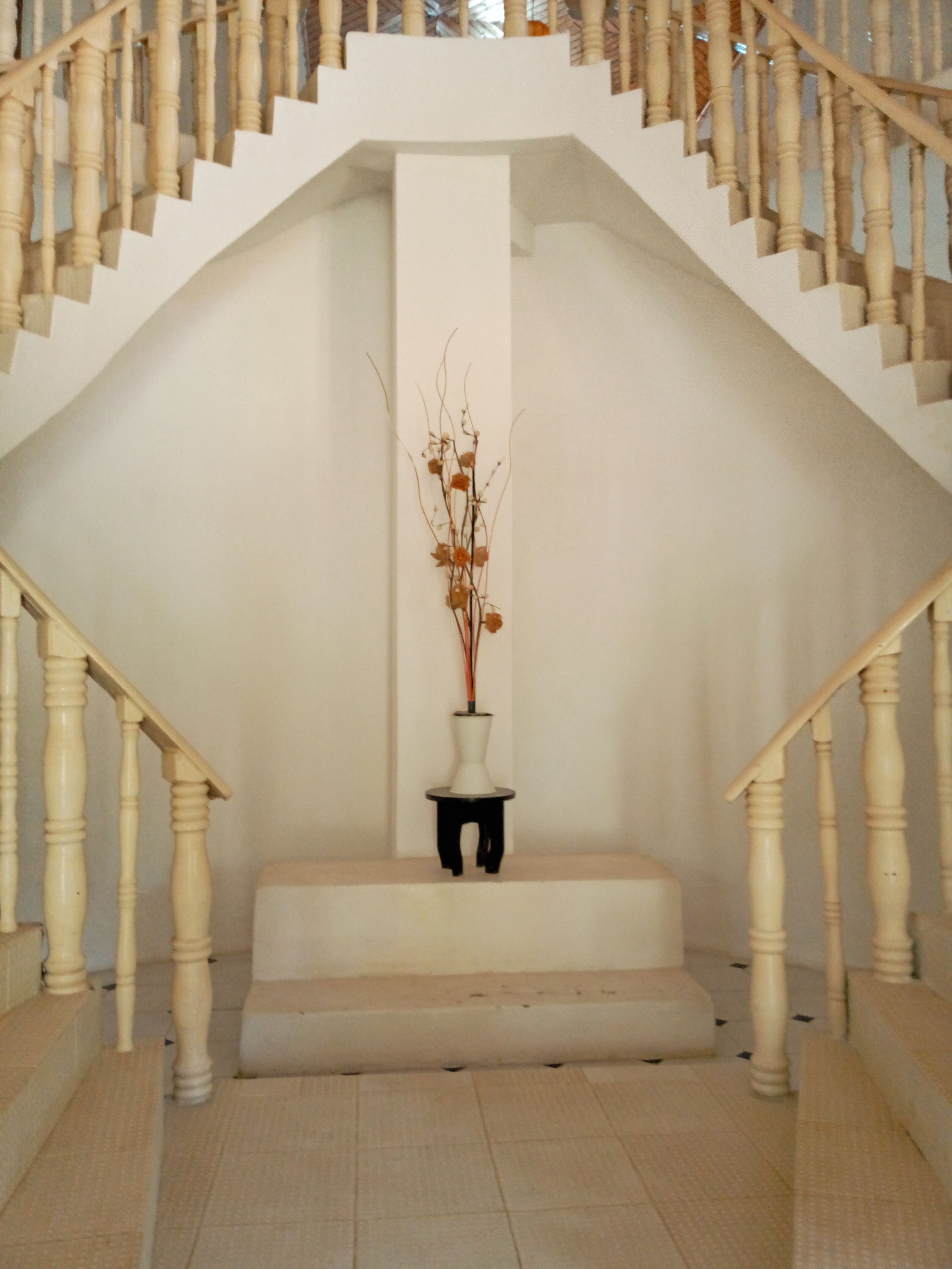 A staircase with white balusters and a white vase with branches on a small platform.