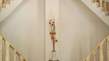 A staircase with white balusters and a white vase with branches on a small platform.