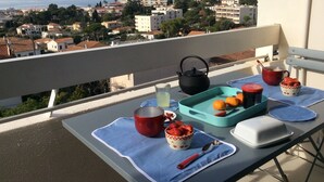 A balcony with a table set for a meal, featuring a teapot, cups, and a fruit tray. - 3 rooms apartment renovated with panoramic sea view (antibes)
