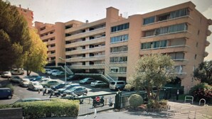 A multi-story building with a parking lot in front. - 3 rooms apartment renovated with panoramic sea view (antibes)