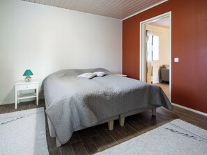Un dormitorio con una cama, una mesita de noche, una lámpara y una puerta que da a otra habitación.