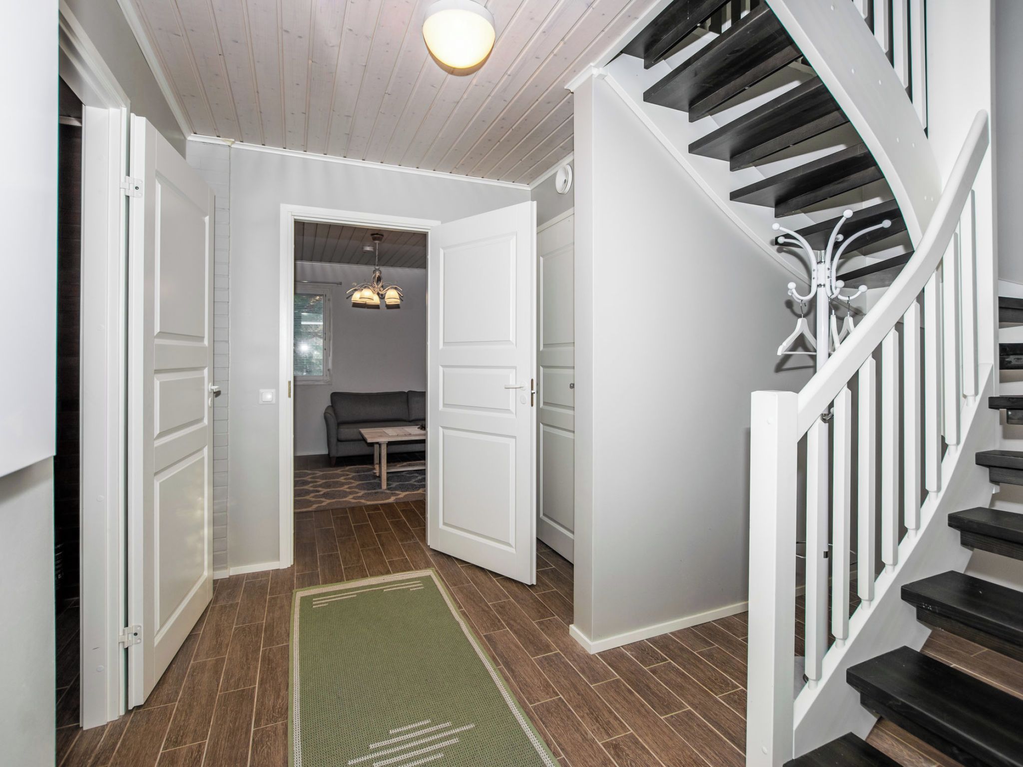 A hallway with a staircase, a bench, and a door leading to another room.