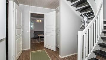 A hallway with a staircase, a bench, and a door leading to another room.
