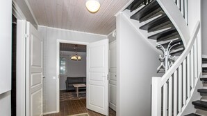 A modern interior with a staircase, a hallway leading to a living area, and a dining table.