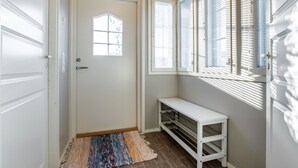 A hallway with a white door, a small window, and a white bench.