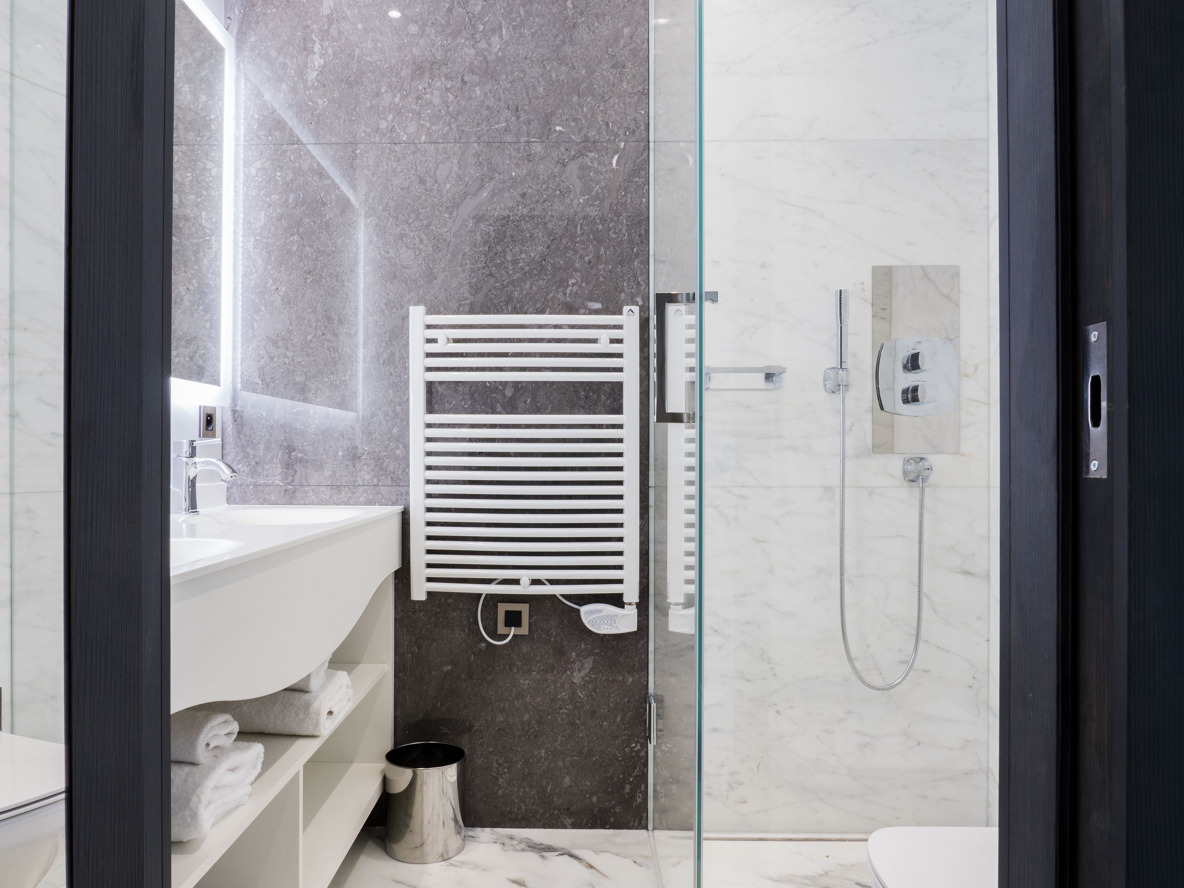 Ein modernes Badezimmer mit einer Duschkabine aus Glas, einem weißen Waschbecken und einem Handtuchhalter.