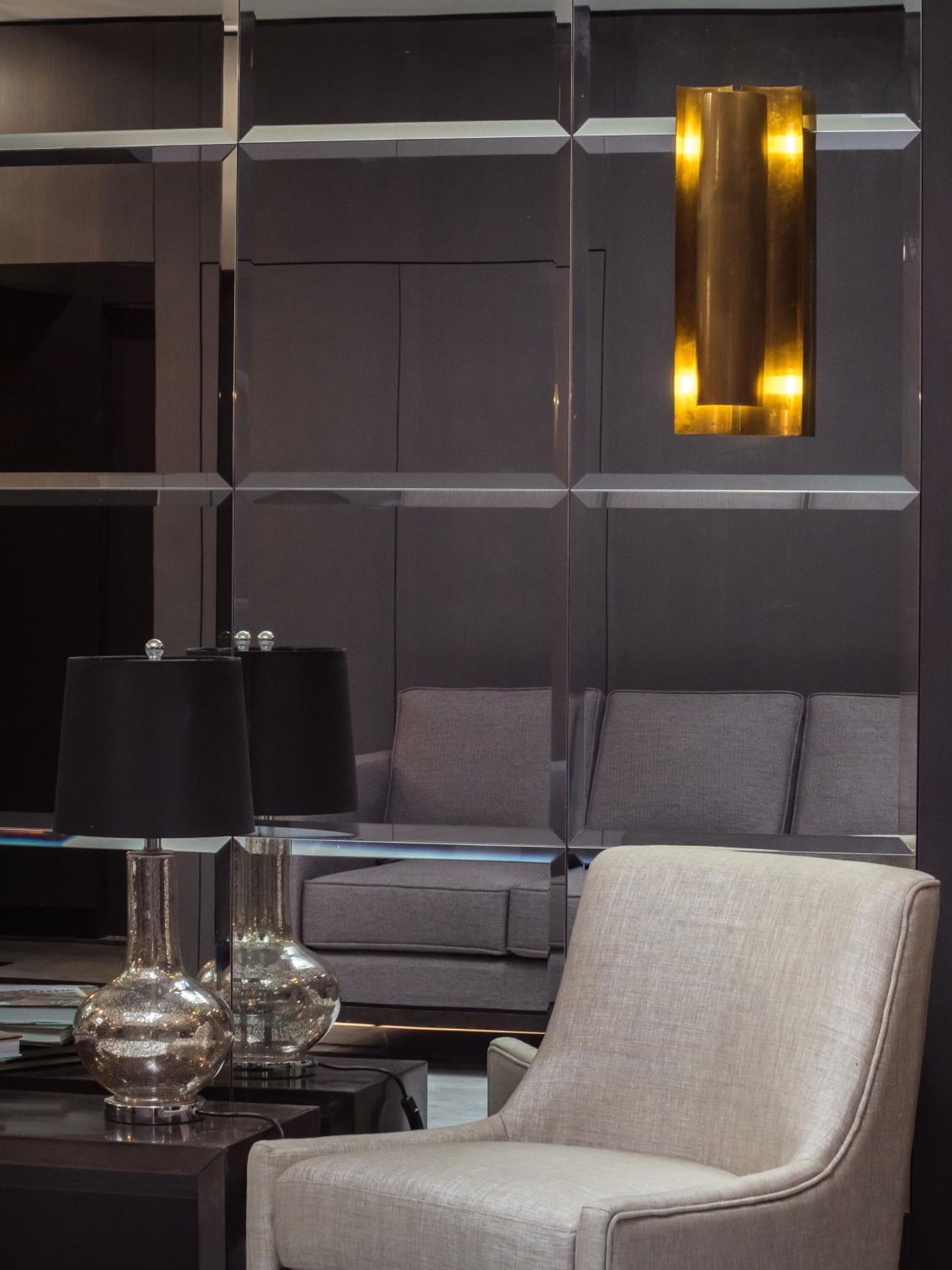 A modern living room with a grey sofa, a glass coffee table, and two lamps.