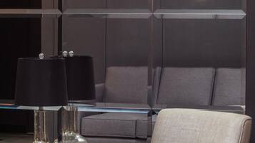 A modern living room with a grey sofa, a glass coffee table, and two lamps.