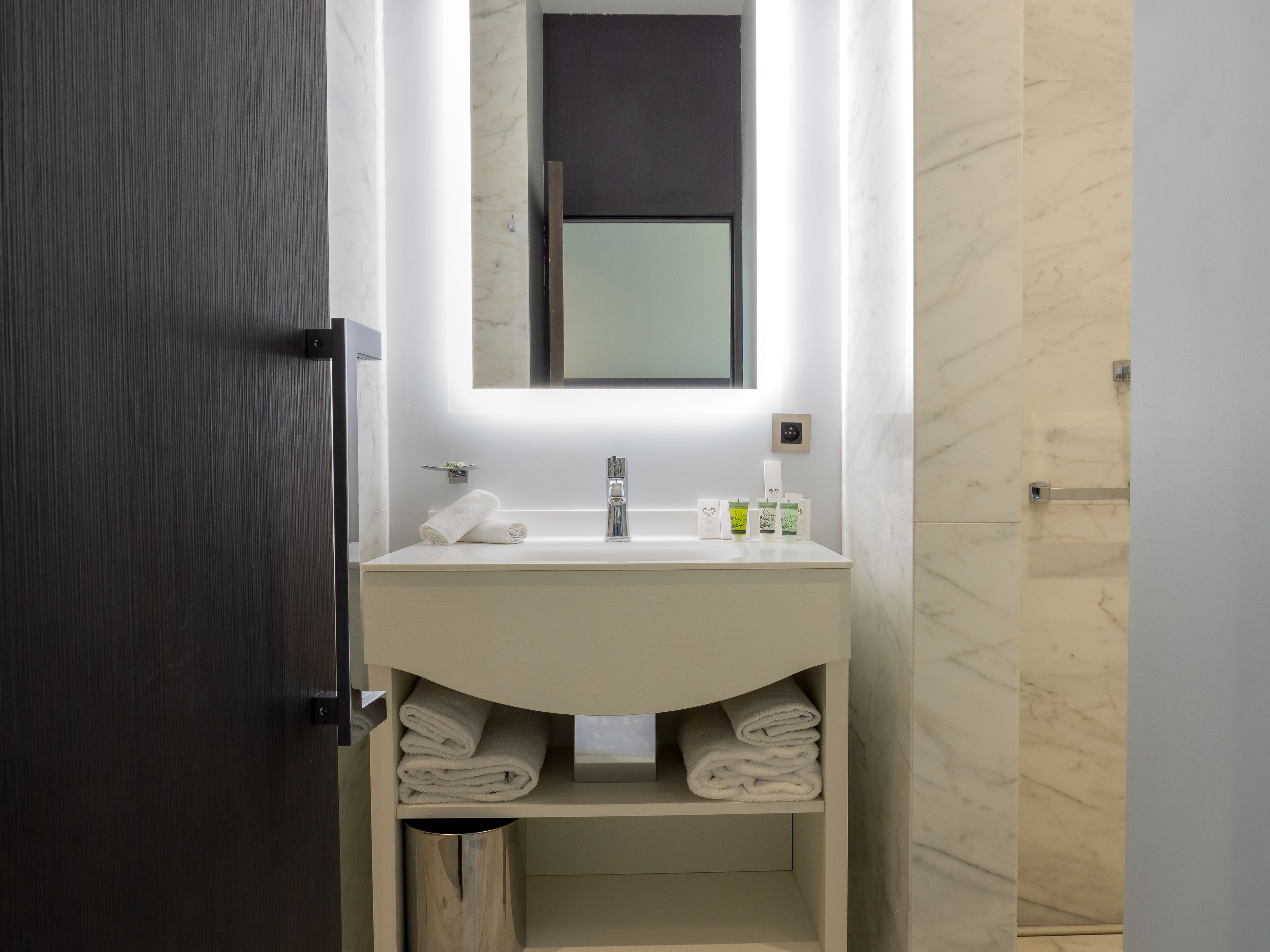 A modern bathroom with a white sink, a mirror, and a towel rack.