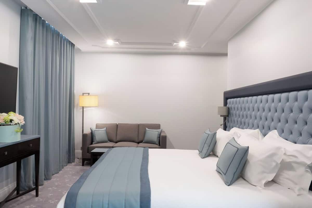 Une chambre d’hôtel moderne avec un grand lit, un canapé, un bureau et une lampe.