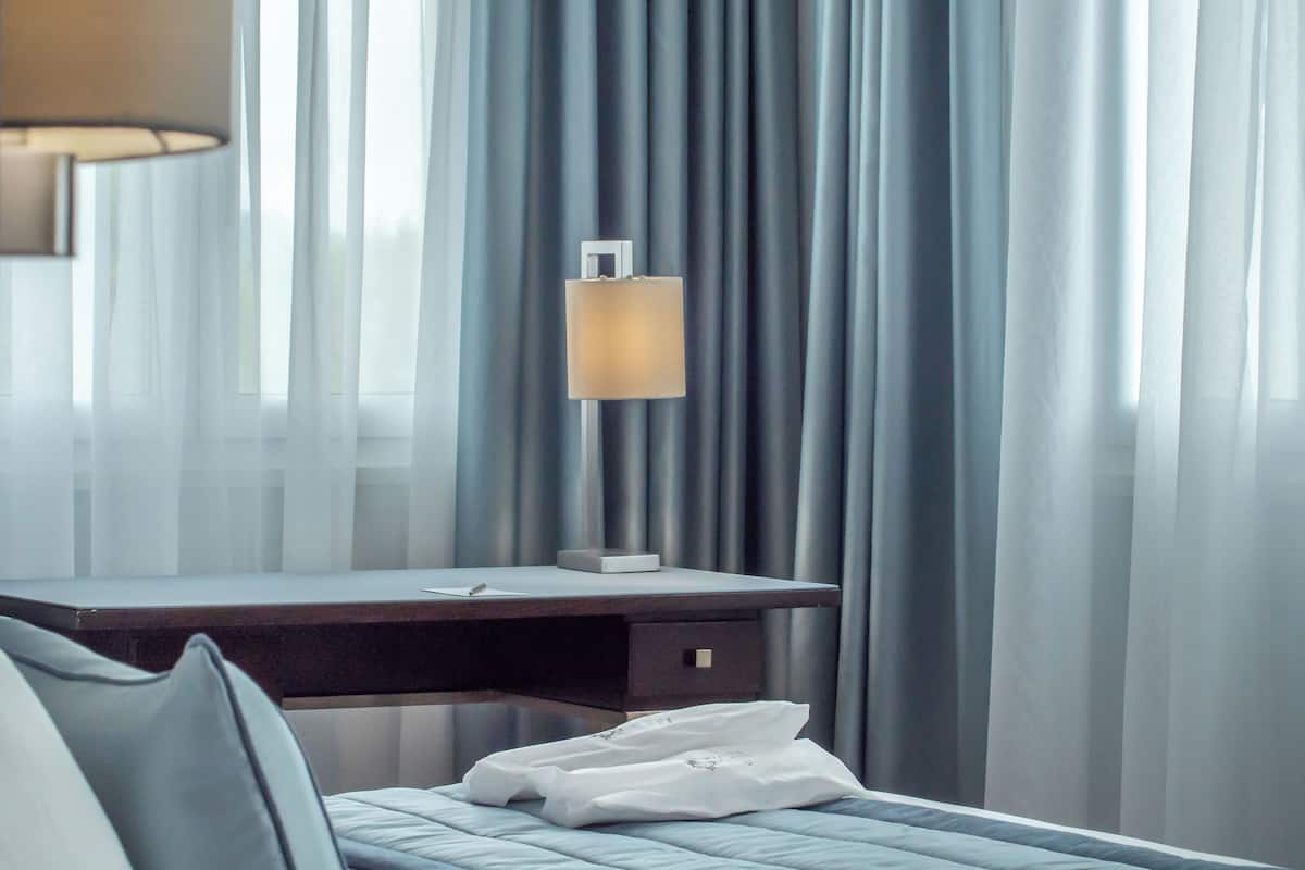 Une chambre d’hôtel avec un lit, un bureau et une lampe.