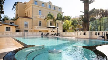 Relax by the inviting pool surrounded by lush greenery and lounge chairs.