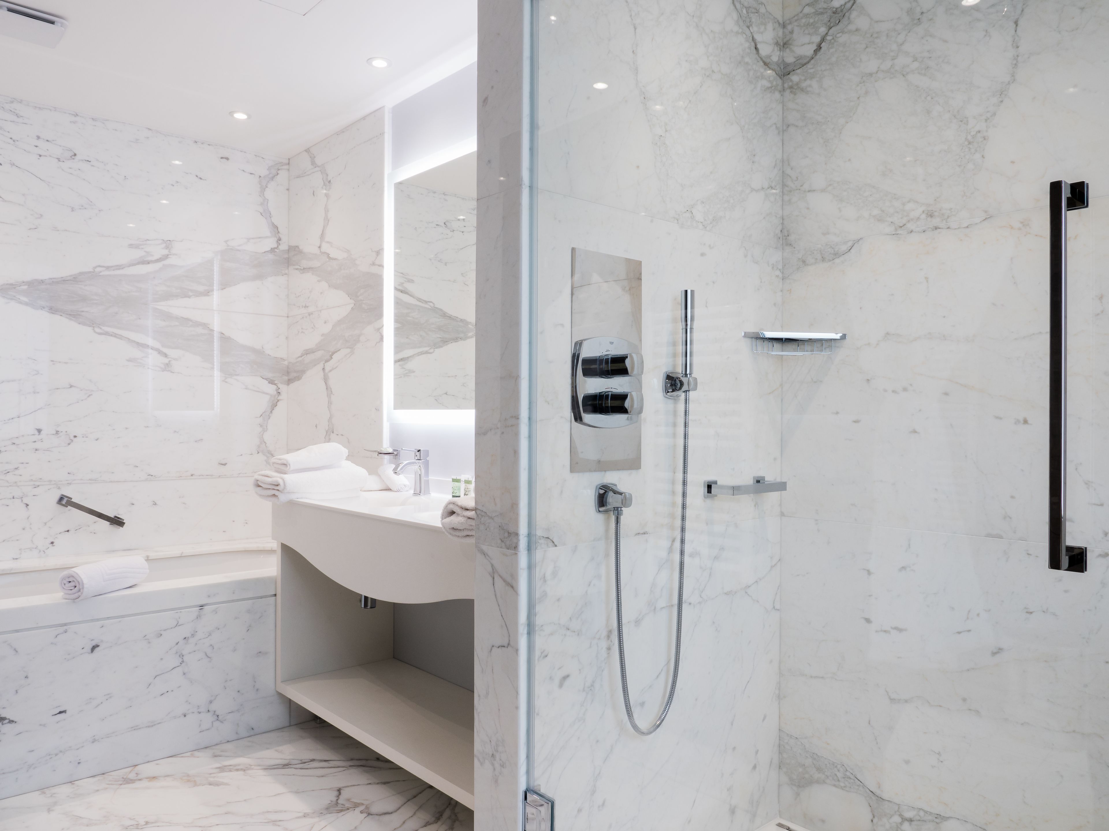 A modern bathroom with a marble shower, a glass-enclosed shower area, and a white sink with a vanity.