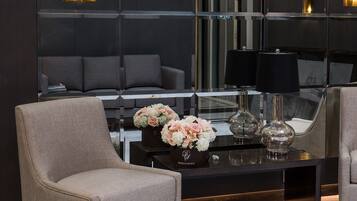 Un vestíbulo moderno con zona de estar, una mesa de centro con elementos decorativos y una gran pared de espejo.