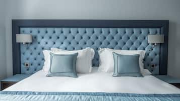 Ein ordentlich bezogenes Bett mit einer gepolsterten Kopfteile, zwei Nachttischlampen und einem blauen Zierkissen.