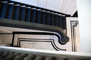 Una escalera con peldaños azul oscuro y paredes blancas con patrones geométricos negros.