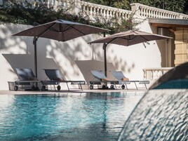 Un área junto a la piscina con sillones de descanso y sombrillas.
