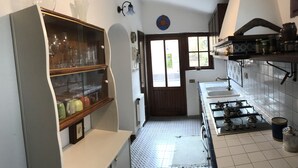 A kitchen with a gas stove, a sink, and a window with a view of the outside. - Holiday home the fish house (Palermo)