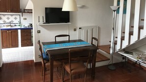A dining area with a table, chairs, a TV, and a lamp. - Holiday home the fish house (Palermo)
