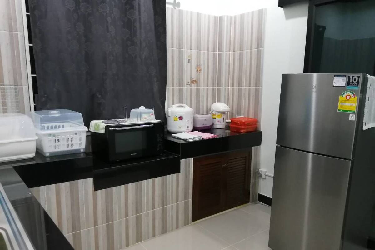 A kitchen with a stainless steel refrigerator, a microwave, and various kitchen appliances on the counter.