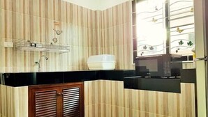 Une cuisine avec un papier peint à rayures, un plan de travail noir, un saladier blanc et un four à micro-ondes.