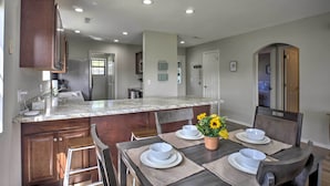 A modern kitchen with a granite countertop, wooden cabinets, and a dining area with a table set for four. - < 1 Mi to Strip! Golfer's Oasis w/ Pool in Branson (Branson)