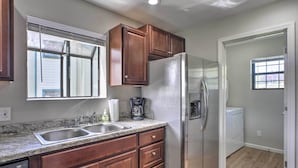 A kitchen with wooden cabinets, a stainless steel refrigerator, a dishwasher, and a window with blinds. - < 1 Mi to Strip! Golfer's Oasis w/ Pool in Branson (Branson)