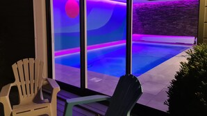 Un espace piscine moderne offrant une vue sur le coucher du soleil à travers de grandes fenêtres.