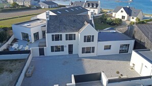 Une maison moderne dotée d’une grande allée et offrant une vue sur la mer.