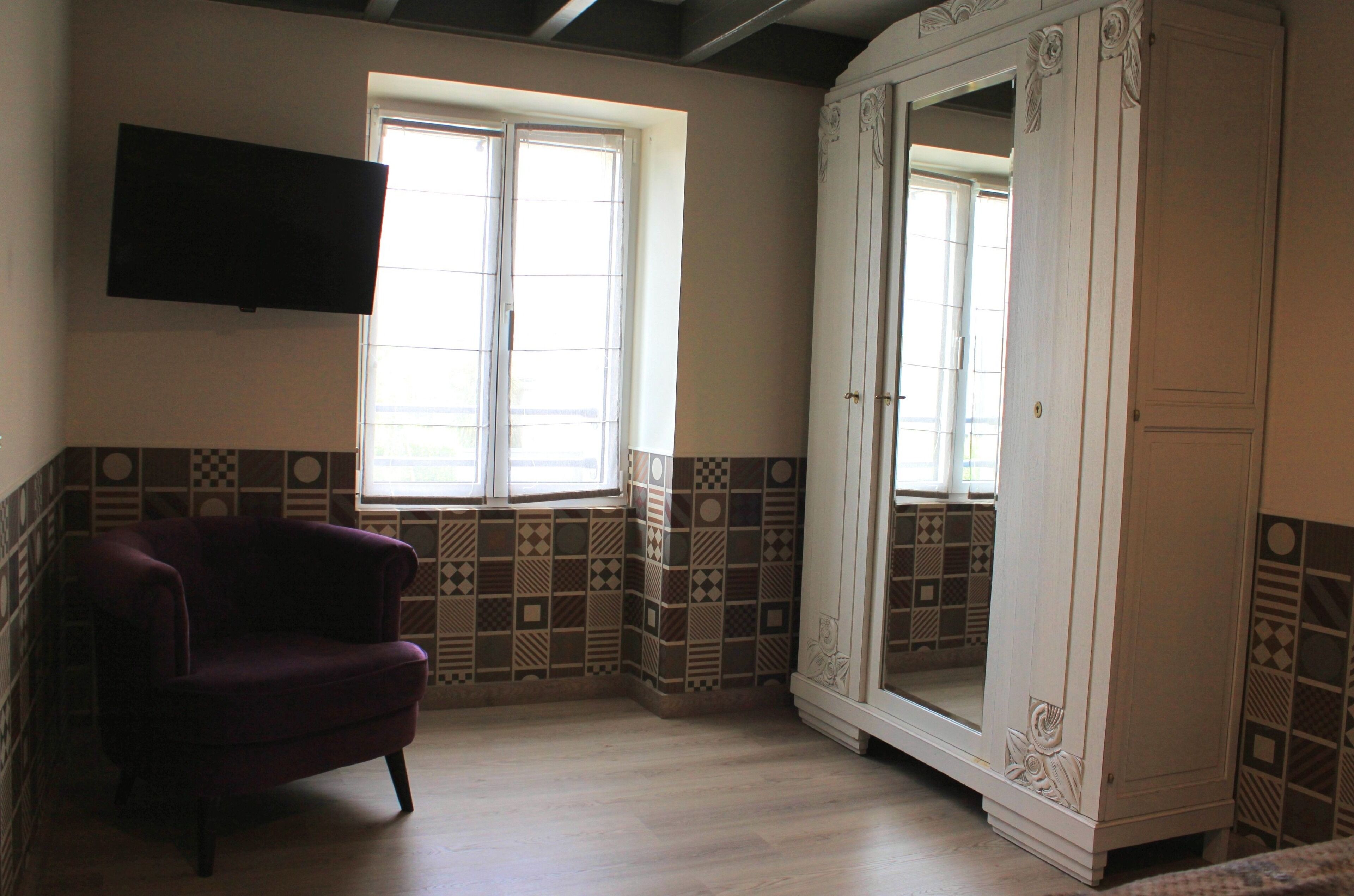 A room with a large mirror, a television, and patterned wall tiles.