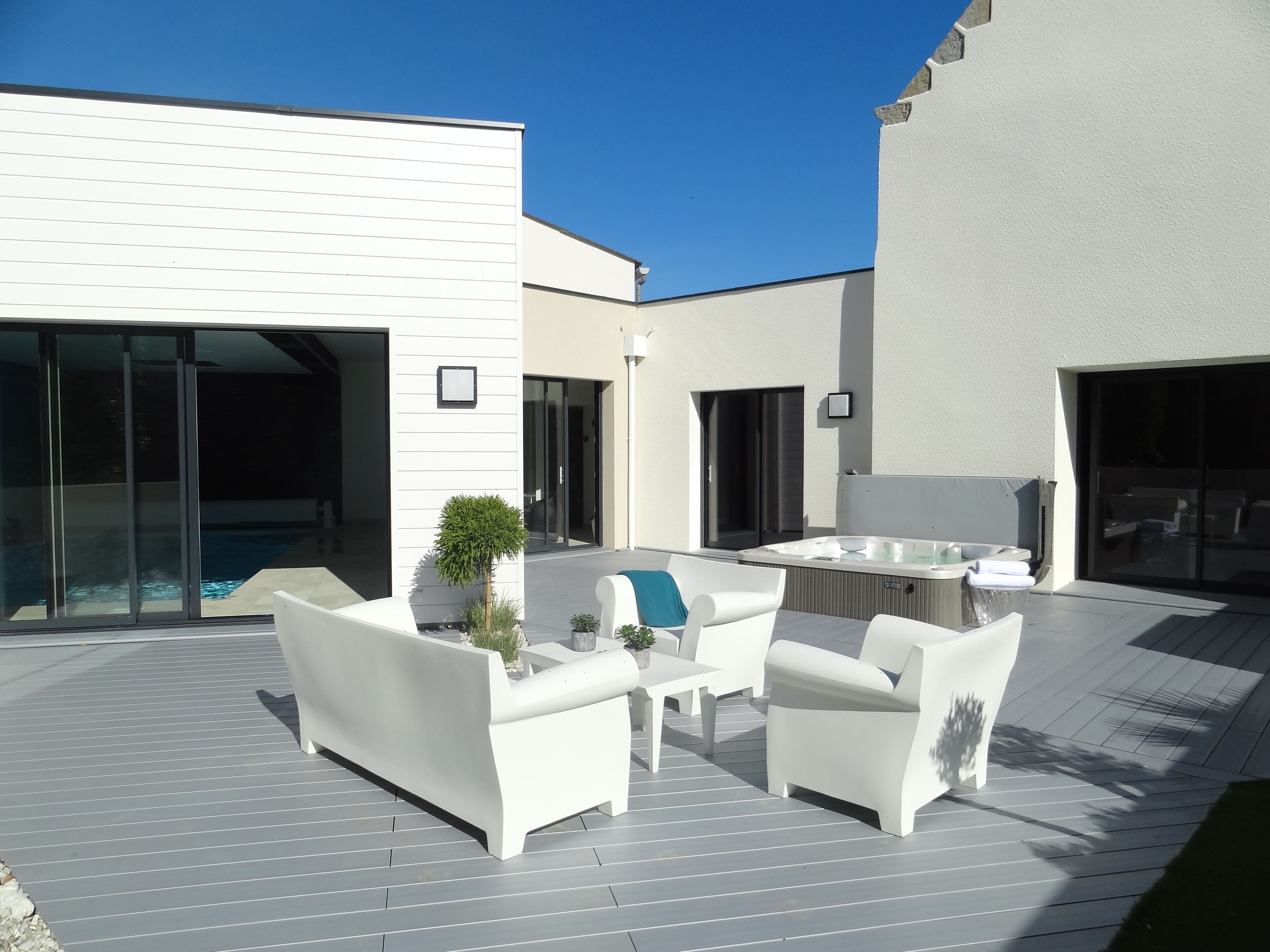 Eine moderne Außenpatio mit weißen Möbeln, einem Whirlpool und einem Swimmingpool.