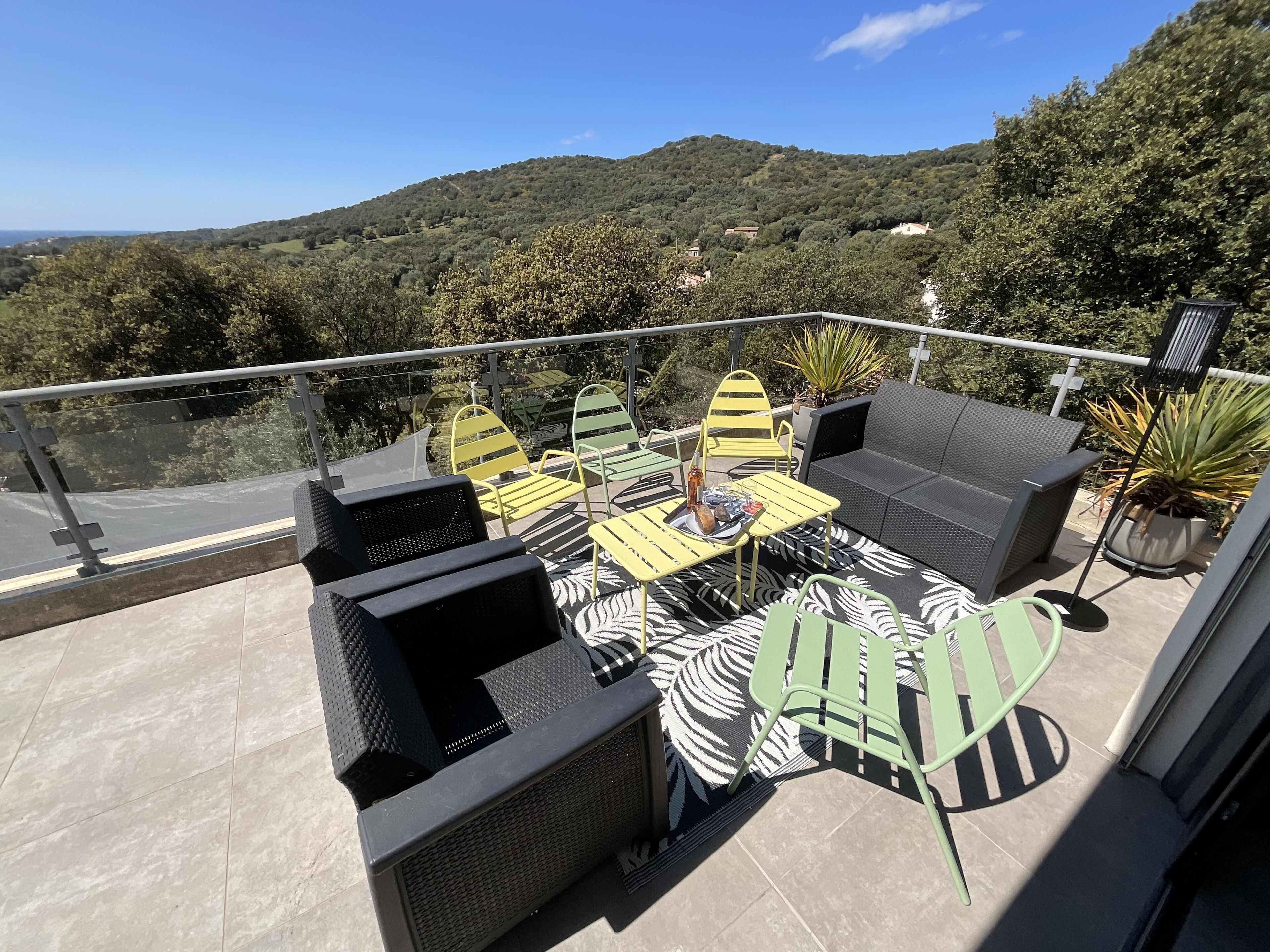Eine Terrasse mit Gartenmöbeln und Blick auf eine Hügellandschaft, versehen mit einem Geländer.