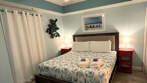 A bedroom with a bed, two nightstands, a wall-mounted plant, a framed picture, and a wooden floor. - Gulf-Front Calypso 1BR/2BA | Free Beach Service (Panama City Beach)