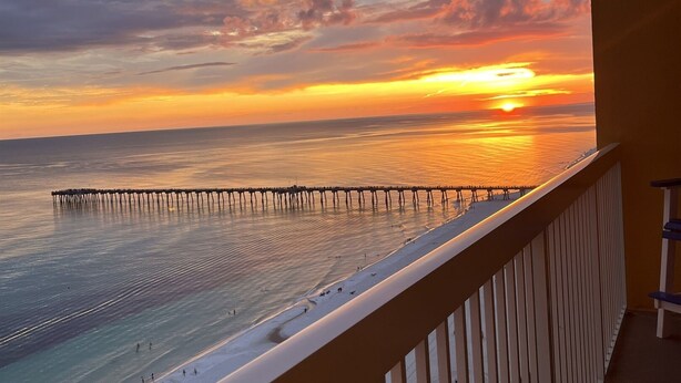 A balcony with a view of a beach and a pier during sunset. - Gulf-Front Calypso 1BR/2BA | Free Beach Service (Panama City Beach)