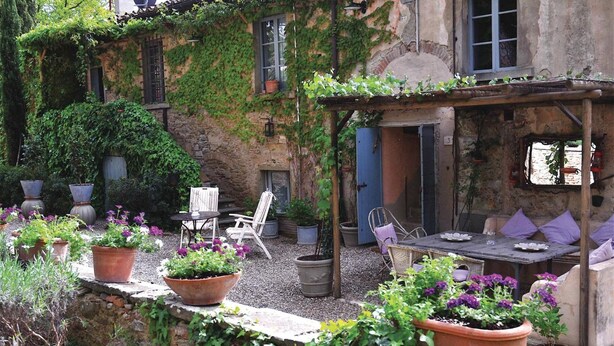 A rustic outdoor seating area with a table and chairs, surrounded by potted plants and a stone wall. - Agriturismo La Striscia (Arezzo)