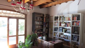 Ein Zimmer mit Holzbalkendecke, Bücherregalen, einem Schreibtisch und einem großen Fenster.