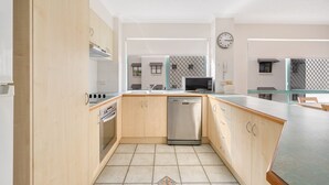 Eine moderne Küche mit Holzschränken, Edelstahlgeräten, einem Geschirrspüler und einer Mikrowelle.