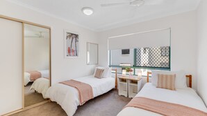 Ein Schlafzimmer mit zwei Einzelbetten, einem Schreibtisch, einem Spiegel und einem großen Kleiderschrank.