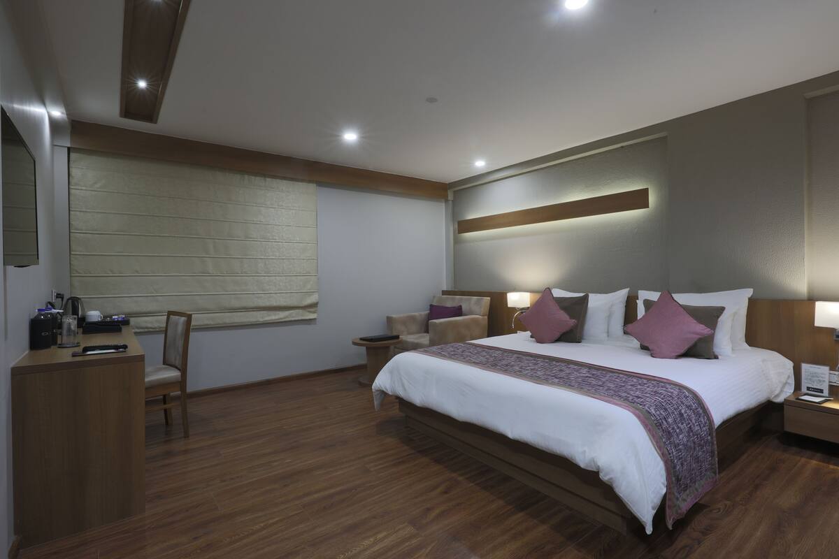 Ein modernes Hotelzimmer mit einem großen Bett, Nachttischen, einem Schreibtisch und einem Stuhl.