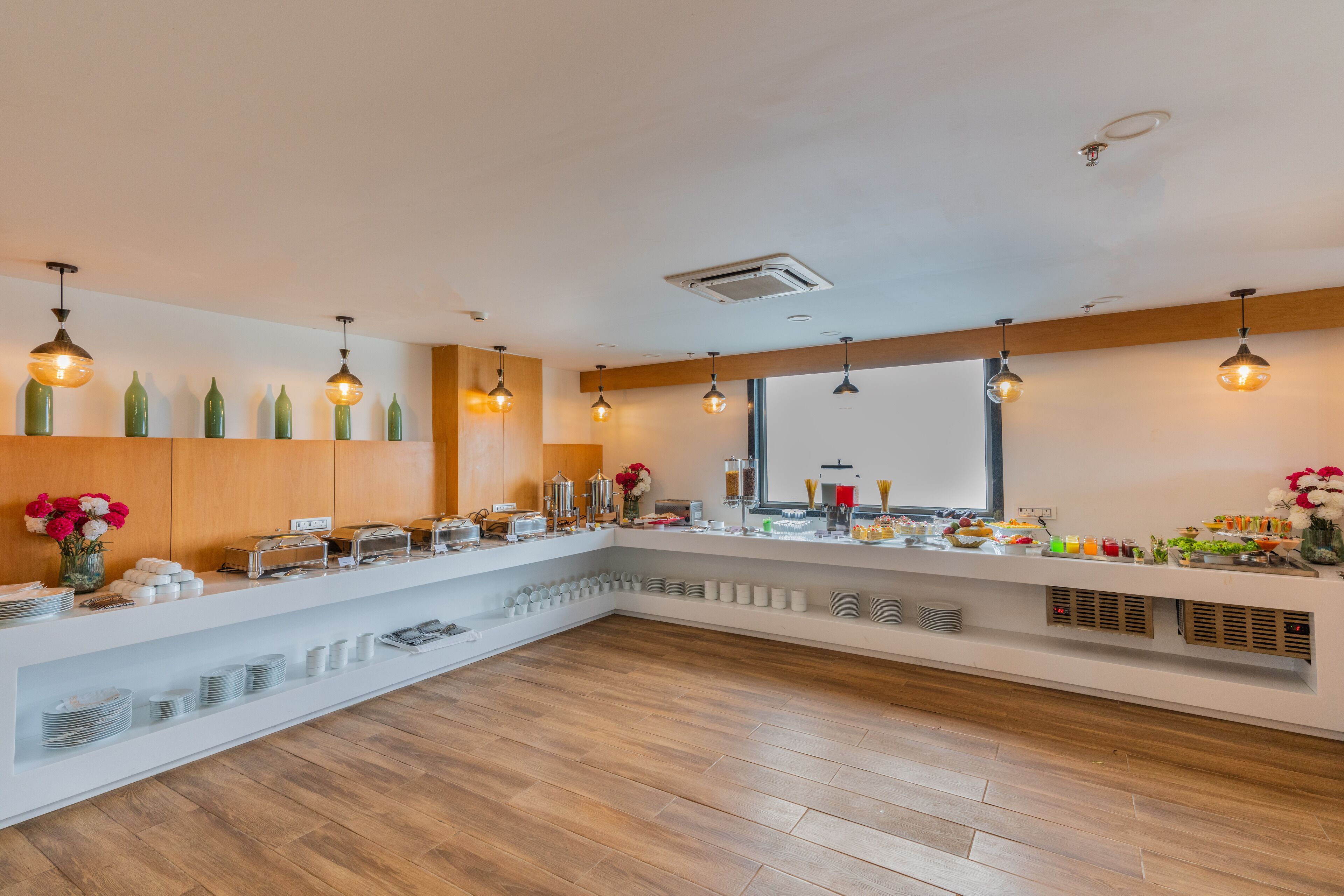 A modern hotel reception area with a white reception desk, wooden flooring, and pendant lighting.