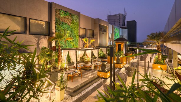 Un patio al aire libre con arreglos de asientos, macetas y una pared con plantas.
