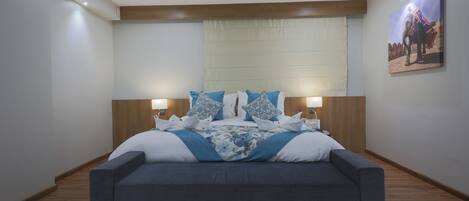 Un dormitorio moderno con una cama grande, cabecera de madera y dos lámparas de noche.