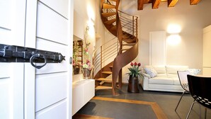 A modern living room with a spiral staircase, a white sofa, and a dining area. - Luxury San Rocco near BELLAGIO (Lezzeno)