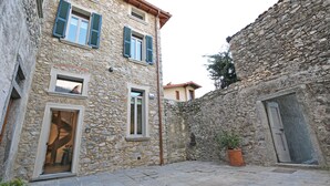 A stone building with a small courtyard, a door, and a window with shutters. - Luxury San Rocco near BELLAGIO (Lezzeno)