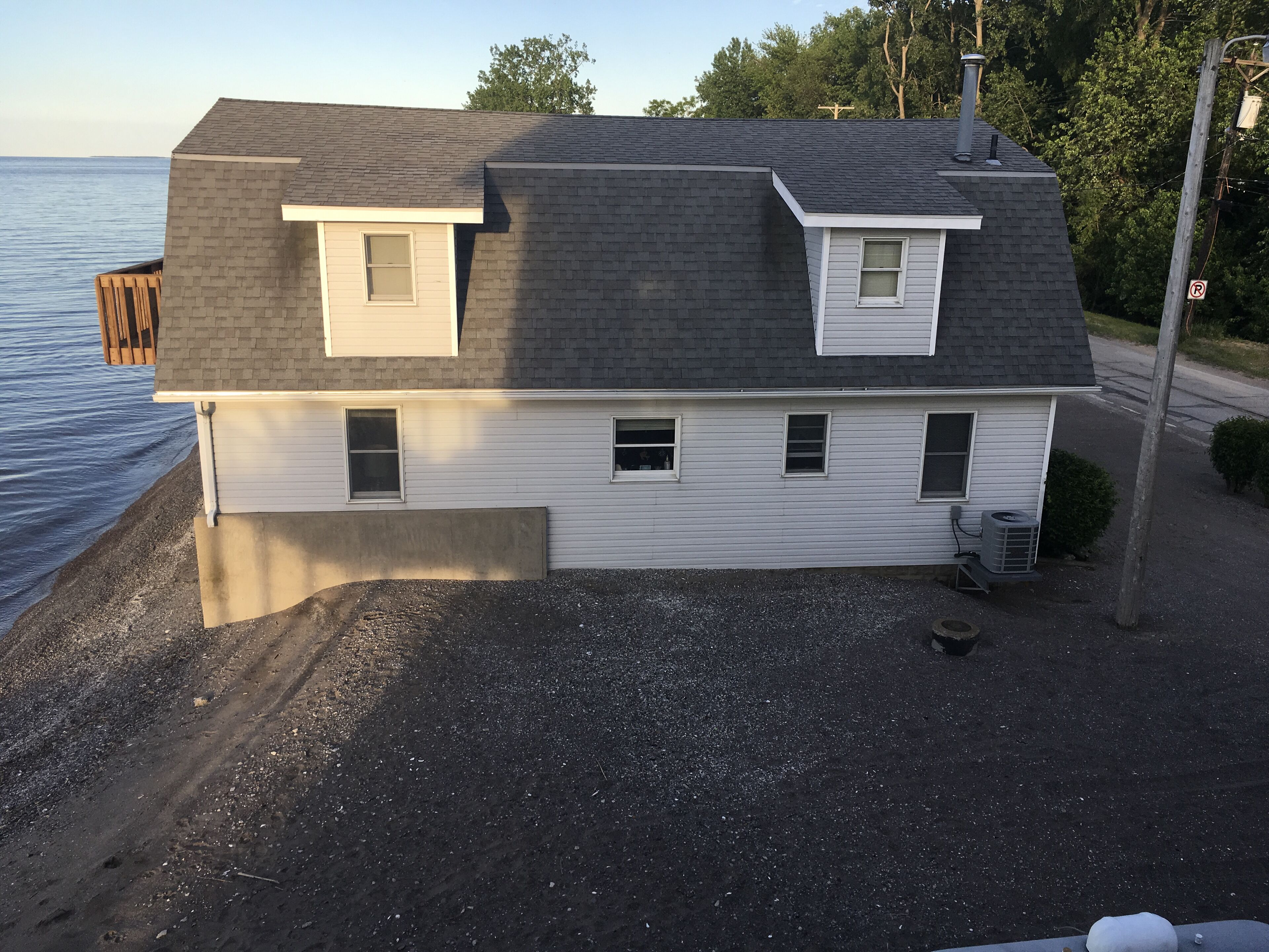 A two-story house with a sloped roof, a small attached garage, and a gravel driveway.