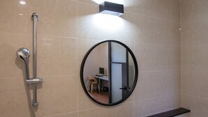 Ein Badezimmer mit Dusche, Spiegel und einer Leuchte.