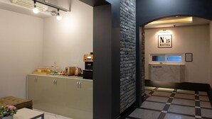 Ein Hotel-Rezeptionsbereich mit Empfangsschalter, Kaffeeautomaten und einem Buffet.