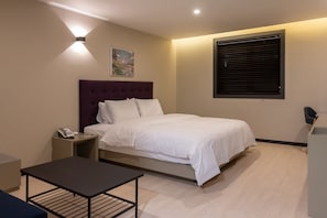 Ein modernes Hotelzimmer mit Bett, Nachttisch und kleinem Schreibtisch.